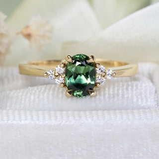 Handmade 18ct yellow gold engagement ring with oval Parti sapphire and diamond cluster photographed at an angle.