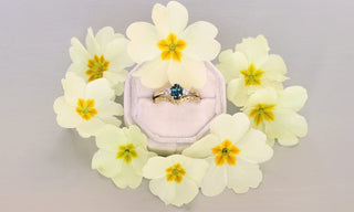Oval teal sapphire and diamond trilogy ring and orange blossom wishbone wedding ring surrounded by primroses 