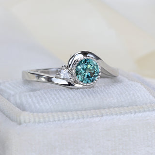 Side view of platinum teal Parti sapphire wave engagement ring showing curved band and bezel setting.