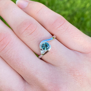 Teal Parti sapphire wave engagement ring in platinum shown worn on hand in natural light.