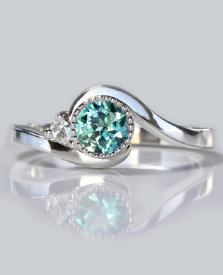 Wave platinum engagement ring set with a teal blue sapphire and diamond accent