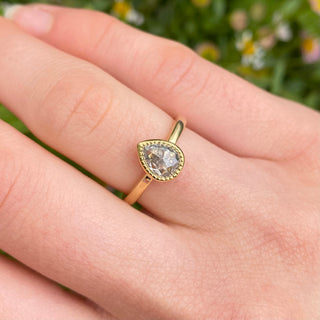 Pear cut salt and pepper diamond engagement ring worn on hand in 18ct gold.