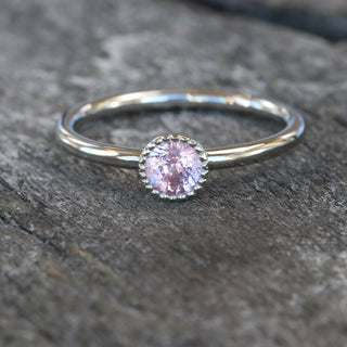 Close up of platinum pink sapphire solitaire ring on grey wood