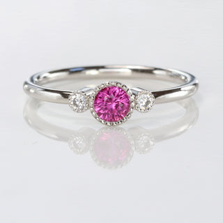 Pink sapphire petite platinum engagement rings with diamonds on a reflective background