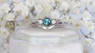 platinum bridal set with teal sapphire and diamond trilogy ring and wishbone wedding ring with engraved border