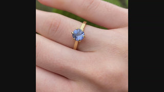 18ct gold lavender sapphire solitaire engagement ring shown worn outdoors.
