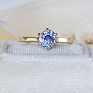 Natural unheated Ceylon sapphire engagement ring photographed on pale fabric.