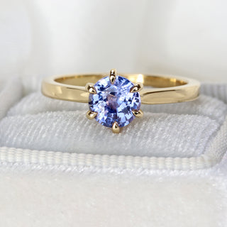 Handmade 18ct gold lavender sapphire ring photographed at an angle on pale fabric.