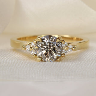 18ct gold engagement ring with salt and pepper diamond and Canadian diamond accents photographed on pale fabric.