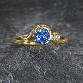 Art Nouveau sapphire engagement ring in 18ct gold photographed on dark textured background.