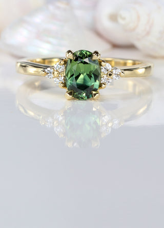 Green sapphire and diamond engagement ring with seashell background