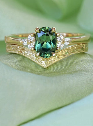 8ct gold green sapphire and diamond cluster engagement ring with orange blossom engraved wishbone wedding band, resting on green ribbon