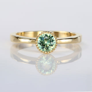 Handmade 18ct gold solitaire engagement ring with natural green sapphire in a milgrain bezel setting.