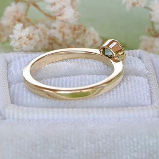 Side view of 18ct gold green sapphire solitaire engagement ring showing raised bezel setting.