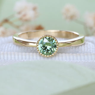 Green sapphire solitaire engagement ring in handmade 18ct gold styled with soft floral background.