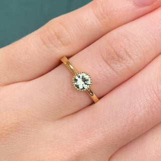 18ct gold green sapphire solitaire engagement ring shown on hand.