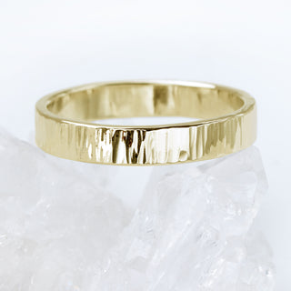 A gold treebark texture ring, posed on a quartz crystal
