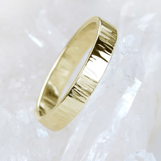 A gold treebark texture ring, posed on a quartz crystal