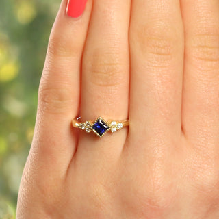 Sapphire and diamond cluster ring shown worn on hand in natural light.