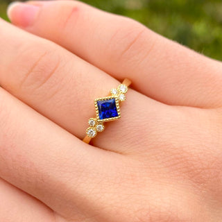 18ct gold princess cut sapphire and diamond ring shown worn on hand.