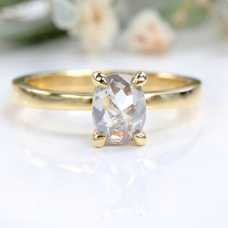 Oval salt and pepper diamond ring photographed against floral background.
