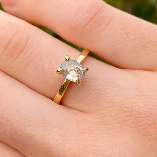 Oval salt and pepper diamond engagement ring worn on hand in 18ct gold.