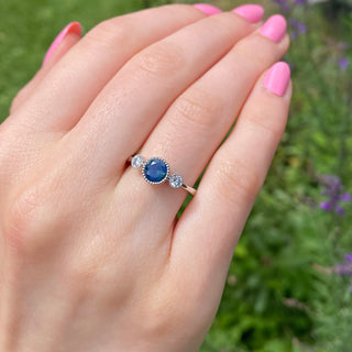 Parti sapphire trilogy engagement ring shown worn outdoors.