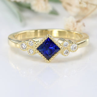 Princess cut blue sapphire and diamond cluster ring in 18ct gold.