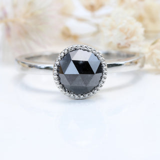 Black diamond platinum solitaire ring with cream floral background.