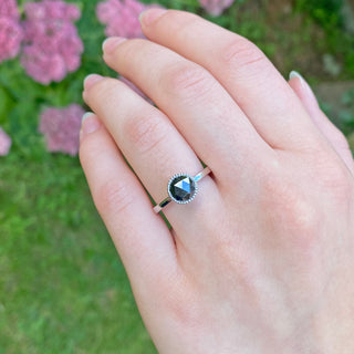 Black diamond engagement ring in platinum shown worn on hand outdoors.