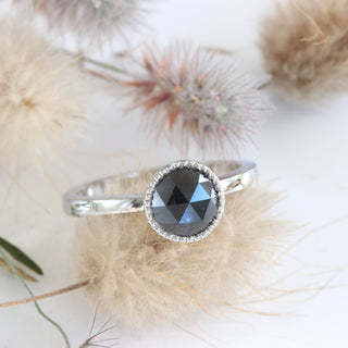 Angled view of platinum black diamond engagement ring with seed heads