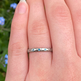 Platinum hammered blue diamond wedding ring worn on hand, handmade in Cornwall.