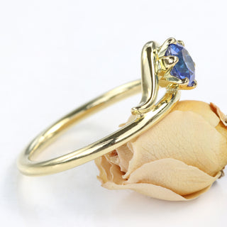 Side view of 18ct gold Art Nouveau sapphire and diamond engagement ring on orange rose flower