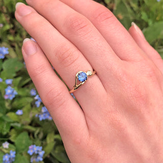 Art Nouveau sapphire engagement ring in 18ct gold shown worn on hand.