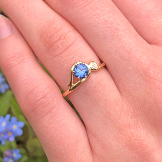 Art Nouveau sapphire engagement ring in 18ct gold shown worn outdoors.