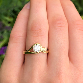 Art Nouveau 18ct gold engagement ring with icy diamond and accent diamond shown on hand.