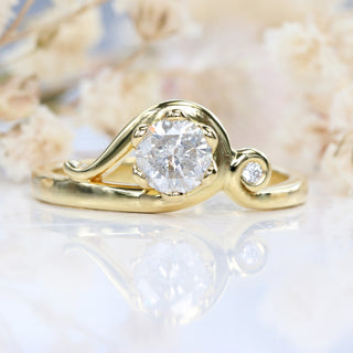 Icy diamond Art Nouveau engagement ring in handmade 18ct gold photographed on light textured backdrop.