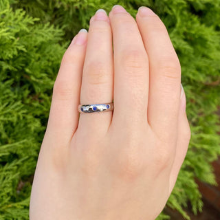 Blue sapphire and diamond eternity or wedding band, worn on the finger