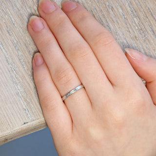 Slim 2mm hammered 18ct white gold half eternity or wedding band, being worn on the finger