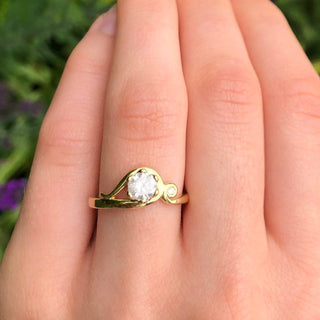 Art Nouveau 18ct gold engagement ring with icy diamond and accent diamond shown on hand.