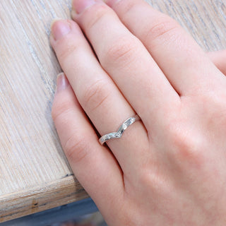 Bead set diamond wishbone wedding ring, handmade by Lilia Nash from solid 950 platinum. Being worn on the hand.