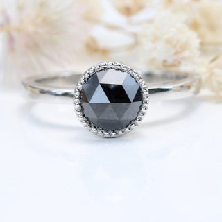 Black diamond platinum solitaire ring with cream floral background.