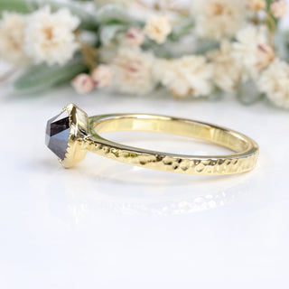 Side view of 18ct gold salt and pepper diamond ring on pale background.