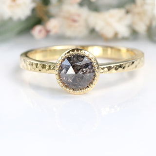 Salt and pepper diamond solitaire ring in 18ct gold photographed on reflective surface.
