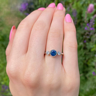 Parti sapphire and diamond platinum trilogy ring on the hand outdoors.