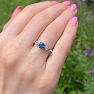 Parti sapphire trilogy engagement ring shown worn outdoors.