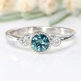 Front view of teal blue sapphire and diamond trilogy engagement ring, handmade from solid 950 platiinum.