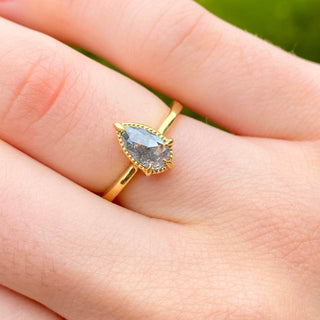 Pear cut salt and pepper diamond engagement ring in 18ct gold shown worn on hand.