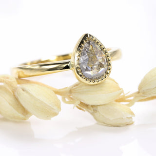 Side view of 18ct gold pear cut salt and pepper diamond engagement ring with bezel setting.