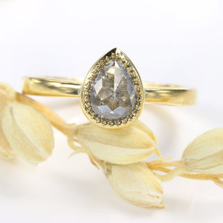 Handmade pear cut salt and pepper diamond engagement ring photographed with seed head.